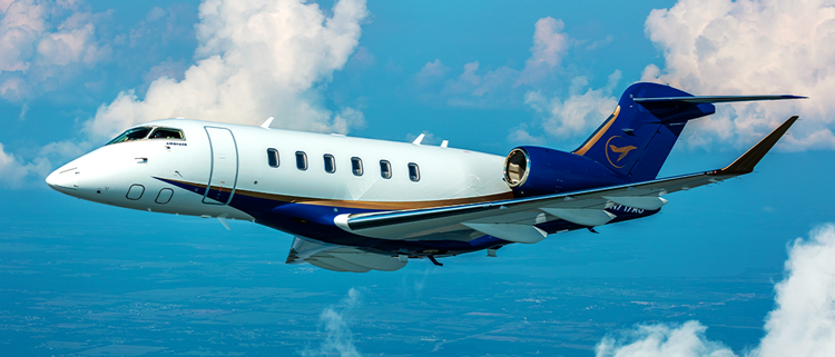 A Challenger 350 in flight with tropic air and beautiful white fluffy clouds in the sky. A crisp light reflects off the plane highlighting the gold accent that cuts down the side of the plane between the white painted body and blue tail and underbody.